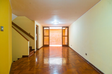 sala de casa con piso de madera y paredes amarillas