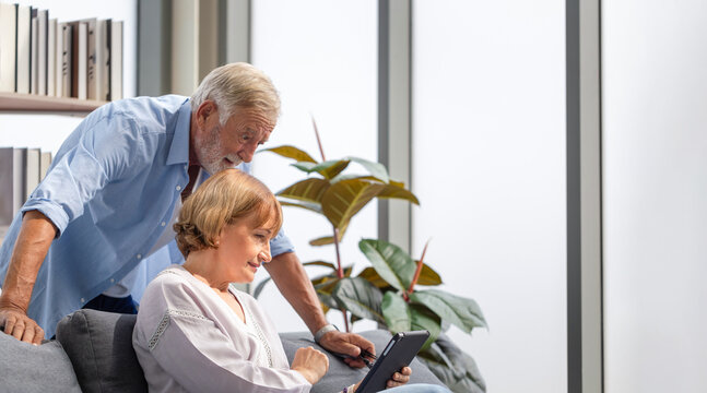 Senior couple in living room, Woman and a man using tablet smartphone doing a video call in living room, Happy family concepts