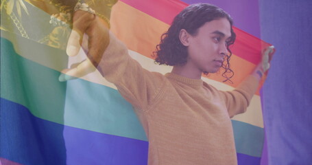 Image of diverse gay male couple holding hands over biracial gay man holding rainbow flag