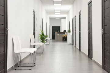 Empty hospital corridor with chairs and doors