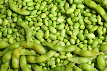 Fresh edamame beans and pods as background, above view