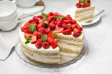 Tasty sponge cake with fresh berries and mint on light gray table, closeup