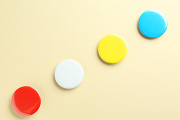 Colorful button badges on beige background, flat lay. Mockup for design