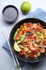 Stir-fry sea food served on light grey table, flat lay