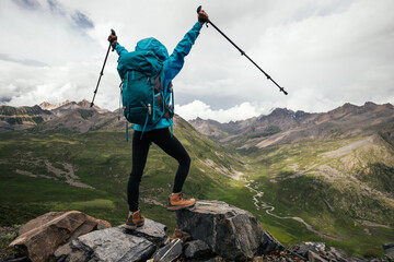 Cheering hiking woman on high altitude mountain top