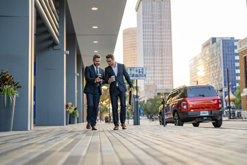 Obraz premium Two businessmen walking and talking in the city. Business men talking. Walking and talking two business men. Colleague walk in New York. Success. Businessmen in suit walking outdoor. City downtown