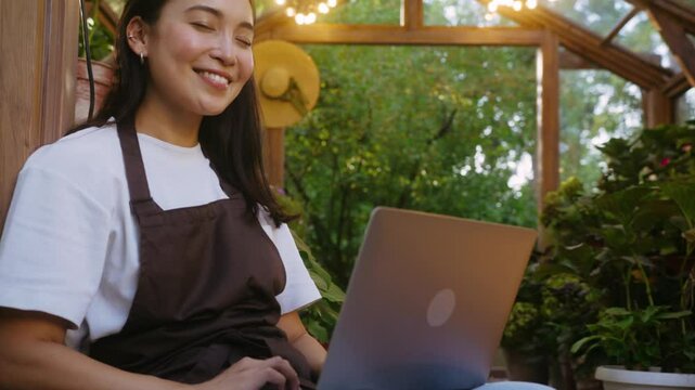 Shop assistant using portable computer surrounded by plants