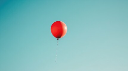 Obraz premium A red balloon floating against a clear sky, symbolizing freedom and celebration in a minimalist outdoor setting.