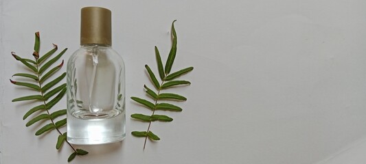 perfume bottle and Pellaea atropurpurea leaves, on a white background