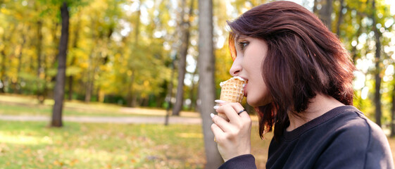 Carefree portrait of a smiling girl relishing a delicious ice cream cone while outdoors.