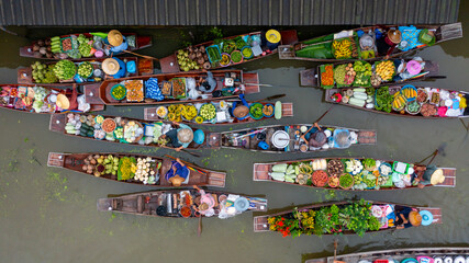 Fototapeta premium Aerial view Damnoen Saduak floating market, Farmer go to sell organic product, fruit, vegetable and Thai cuisine, Tourist visiting by boat, Ratchaburi, Thailand, Famous floating market in Thailand.