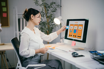 Young woman designs a mobile app, focusing on a colorful wireframe on her computer in a modern office, embracing tech creativity