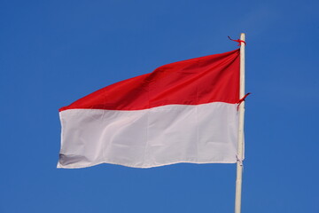 the red and white flag flutters in the wind. the blue sky. the flag of the republic of Indonesia.