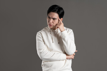 Portrait of Asian man wearing hoodie and posing on gray background.