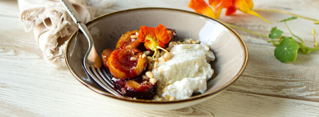 bowl of baked plums with ricotta cheese on light table
