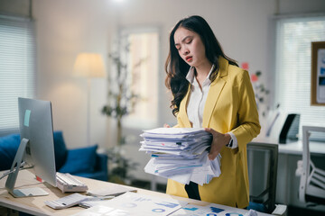 Stressed businesswoman overwhelmed by paperwork in modern office, feeling tired and frustrated....