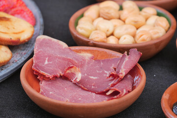A delightful Cured Meat Platter beautifully arranged with various Snacks in rusticstyle dishes