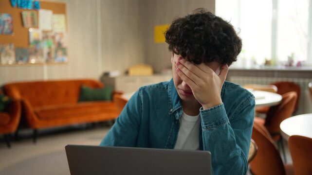 Tired stressed headache overworked sad upset Caucasian male student guy pupil boy teen teenager studying laptop learning online education internet homework prepare to exams school college university