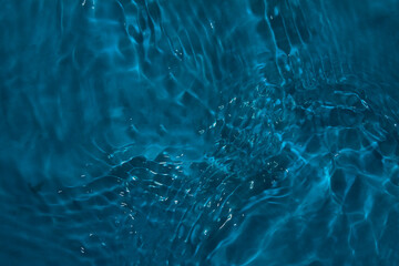 Blue water with ripples on the surface. Defocus blurred transparent blue colored clear calm water surface texture with splashes and bubbles. Water waves with shining pattern texture background.