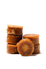 A neatly arranged of traditional brown sugar (gula jawa) cylindrical blocks isolated on a clean white background. The rich, caramel color contrasts beautifully with the crisp, minimalist backdrop