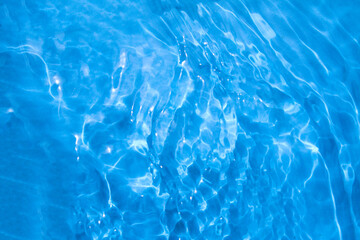 Blue water with ripples on the surface. Defocus blurred transparent blue colored clear calm water surface texture with splashes and bubbles. Water waves with shining pattern texture pool