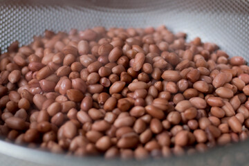 Closed up of cooked peanut with shell in stainless steel sieve