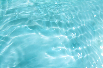 Blue water with ripples on the surface. Defocus blurred transparent blue colored clear calm water surface texture with splashes and bubbles. Water waves with shining pattern texture background.