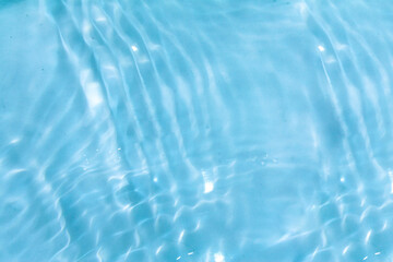 Blue water with ripples on the surface. Defocus blurred transparent blue colored clear calm water surface texture with splashes and bubbles. Water waves with shining pattern texture background.