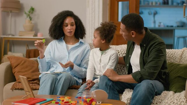 African American mother speech therapist hold letter teach pronounce sound word talk correct pronunciation father dad family child together teamwork progress development preschool man woman daughter