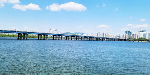 Obraz premium panorama view of the river, Yeouido Hangang River Park, in Seoul, Korea, with a broad bridge, and a cityscape in the backdrop 