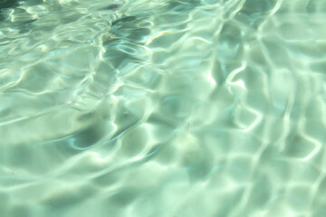 Defocus blurred transparent green colored clear calm water surface texture with splashes and bubbles. Trendy abstract nature background. Water waves in sunlight with copy space. Green water shine