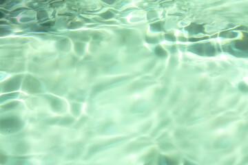 Obraz premium Defocus blurred transparent green colored clear calm water surface texture with splashes and bubbles. Trendy abstract nature background. Water waves in sunlight with copy space. Green water shine