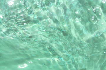 Defocus blurred transparent green colored clear calm water surface texture with splashes and bubbles. Trendy abstract nature background. Water waves in sunlight with copy space. Green water shine
