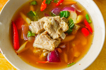 Spicy spare rib pork with pork and vegetable in bowl on wooden table.Popular Thai and Chinese foods.Spicy and sour hot bone soup