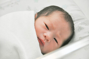 First day newborn Asian baby.Cute Little Caucasian Newborn Baby Lying in Bassinet in Hospital. Happy family and baby concept. Healthcare, Pregnancy and Motherhood.