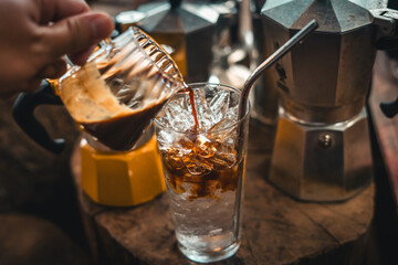 Making iced coffee. Pouring coffee into a glass with ice.