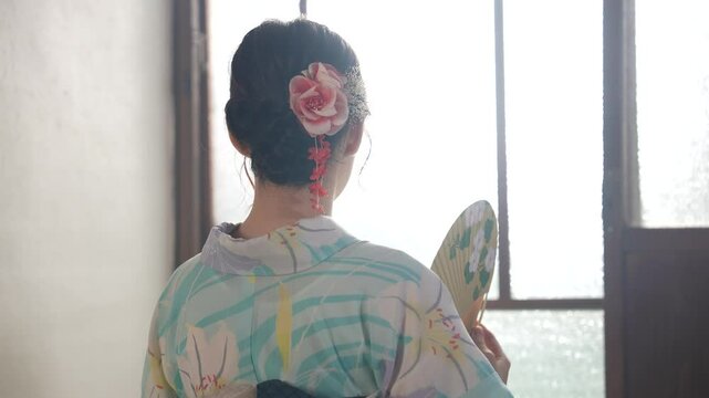 京都の古民家で浴衣を着た女性がうちわで涼んでいる