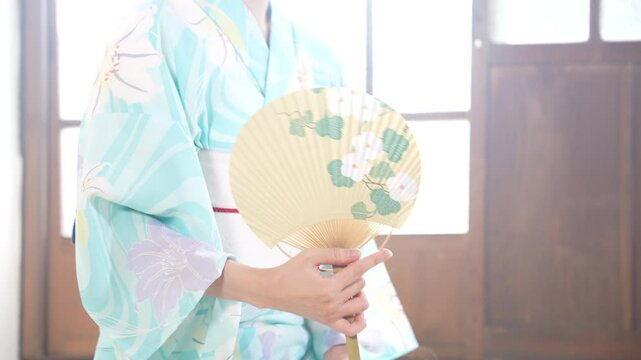京都の古民家で浴衣を着た女性がうちわで涼んでいる