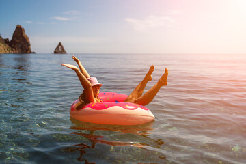 Summer vacation woman in hat floats on an inflatable donut mattress. Happy woman relaxing and enjoying family summer travel holidays travel on the sea.