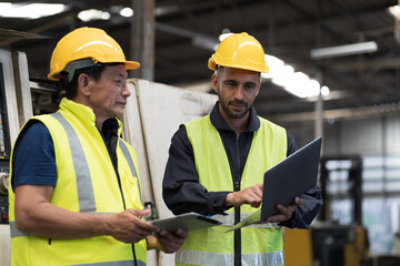 Two male engineer worker discuss and working together in industry factory. Male engineer repairing or maintenance CNC machine in factory