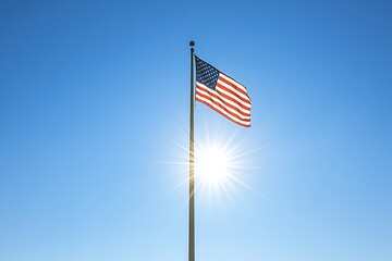 American flag waving against clear blue sky with sun flare