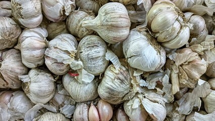 Close-up image of fresh garlic in the market, showing the natural texture and earthy tone. Suitable for themes related to food, agriculture or cooking