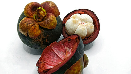 Ripe mangosteen fruit (Garcinia Mangostana Linn) with dark purple skin, revealing the fresh, white interior of the fruit, isolated on a white background.
