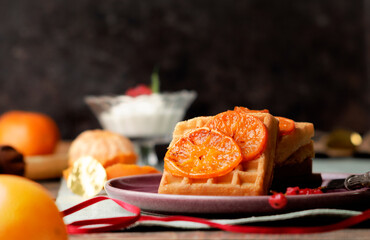 Sweet Belgian waffles with caramelized orange on a pink purple plate. Christmas breakfast. Xmas theme.