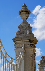Ornate stone pillar stands against a vibrant blue sky in a historic courtyard, showcasing intricate craftsmanship and architectural beauty