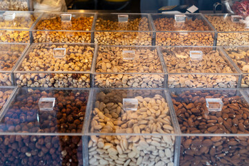 Assorted nuts displayed in clear containers at a market stall in the late afternoon