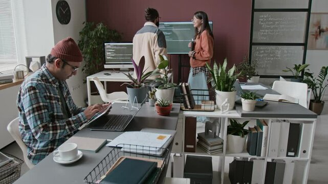 Full timelapse shot of multiethnic male and female software developers interacting during routine workday in IT company office, discussing project algorithms, writing code, consulting colleagues