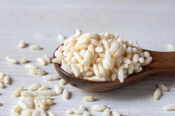 Closeup of Puffed Rice or Popped Rice on a Wooden Spoon Isolated on White Background with Copy...
