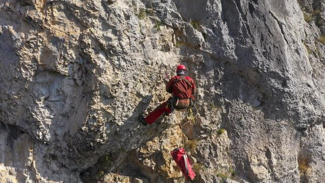 Aerial view of mountain rescuer doing rescue operations hanging on a rope