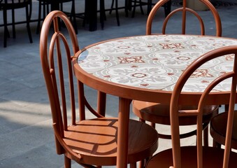 Outdoor cafe or restaurant round table and empty brown chairs furniture object isolated on horizontal ratio stone floor and sunny day natural lights environment background.